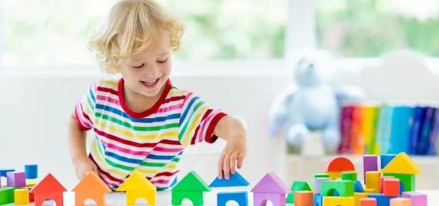 Chłopiec w kolorowej koszulce bawi się klockami